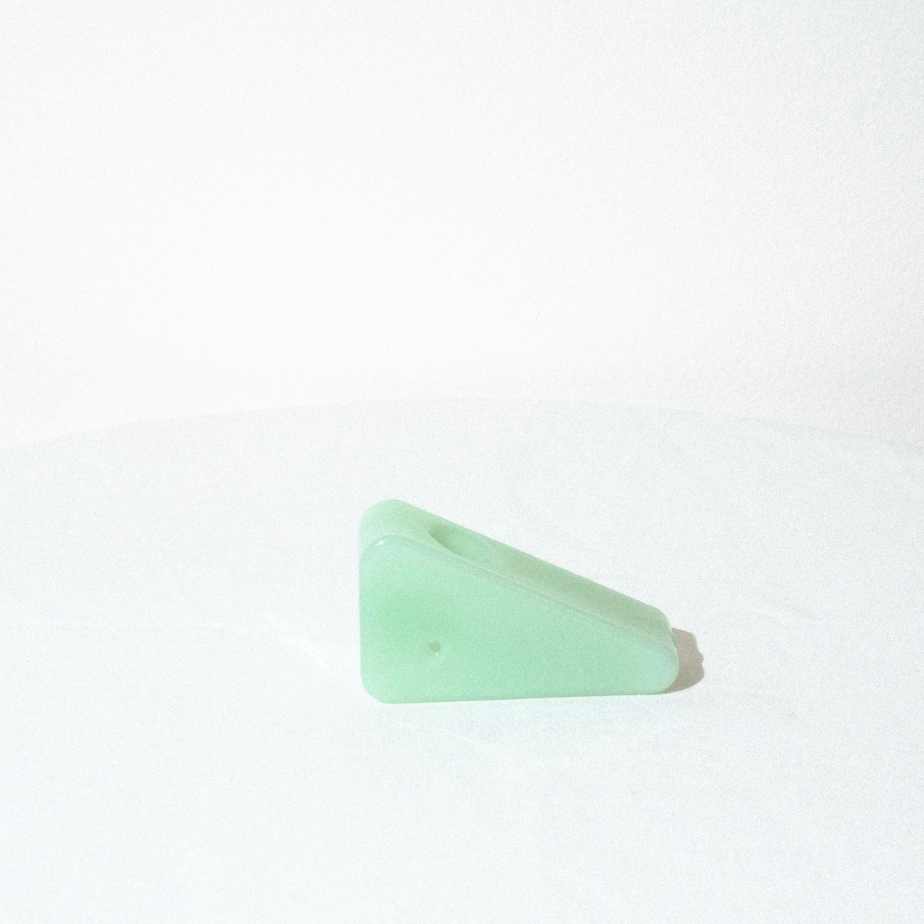 the yew yew triangle pipe in opaque green, side view which features the carb hole.